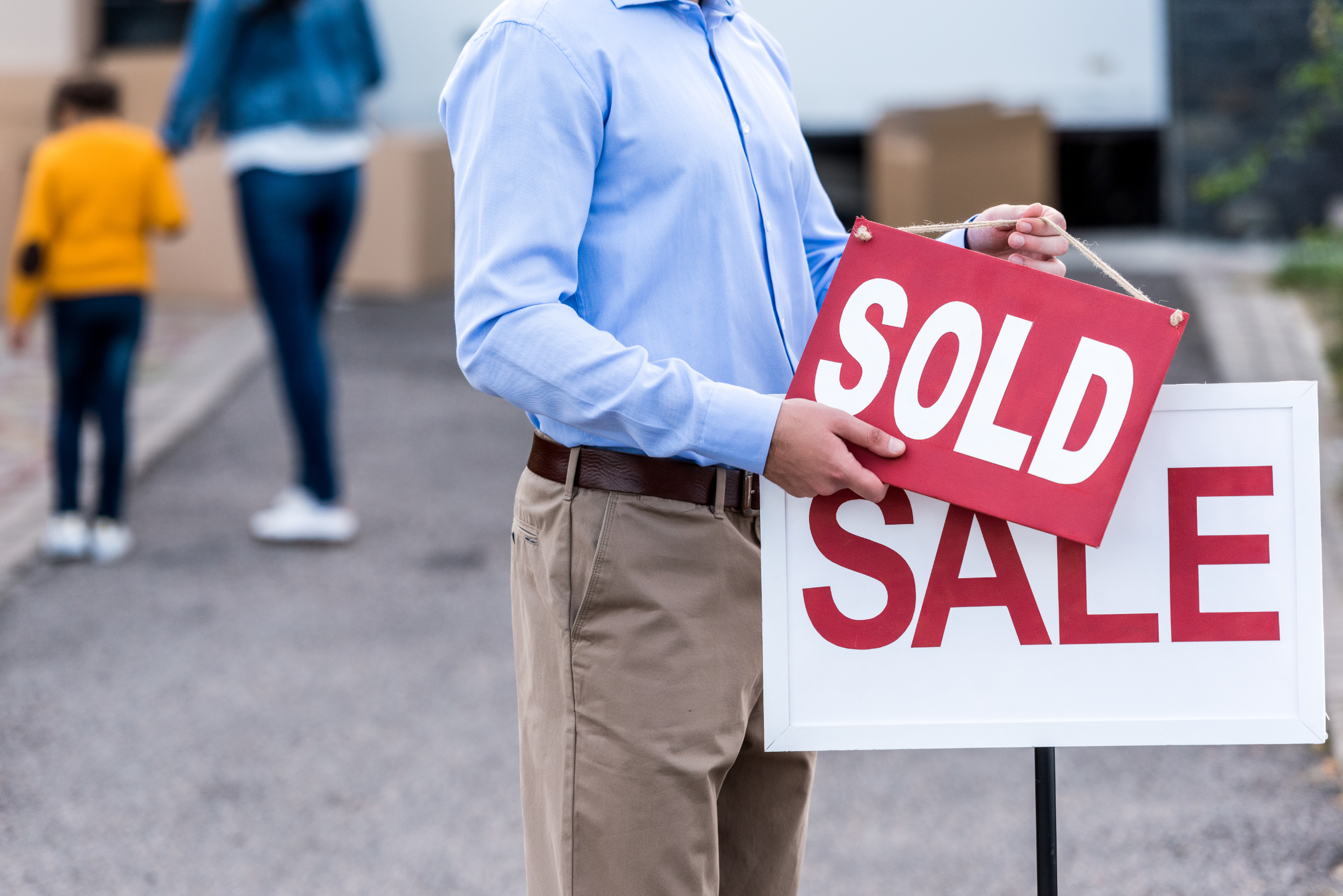 A realtor putting a sold sign in front of a house A realtor putting a sold sign in front of a house