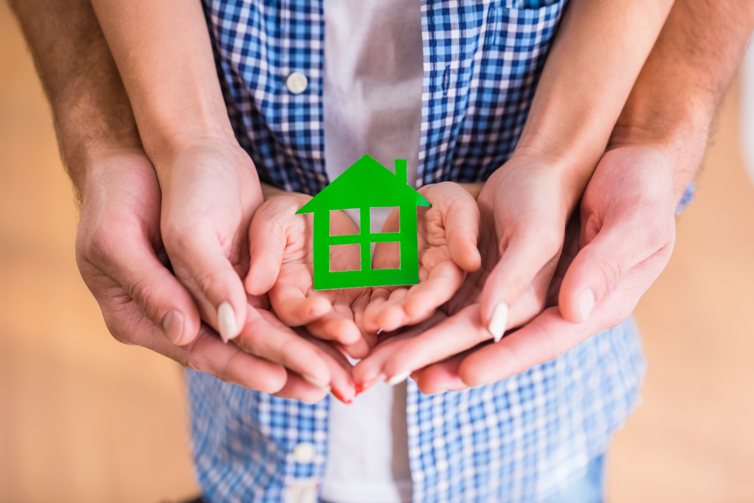 A family holding a green house shaped cutout A family holding a green house shaped cutout